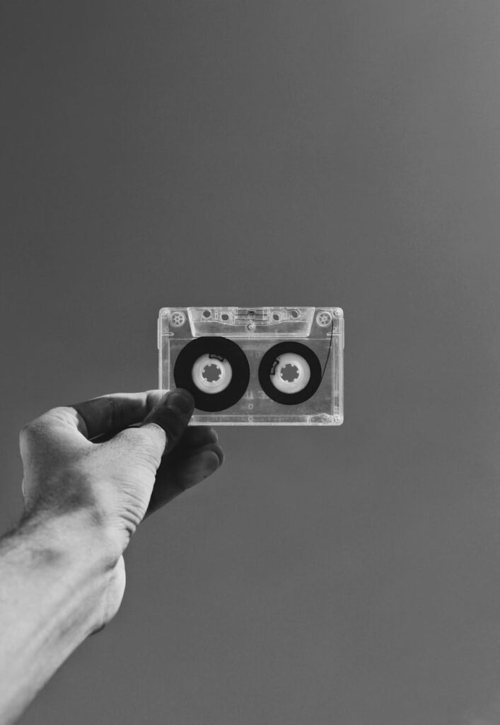 grayscale photography of person holding cassette tape