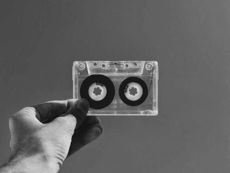 grayscale photography of person holding cassette tape