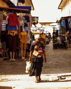 a woman walking down a street with a baby on her back