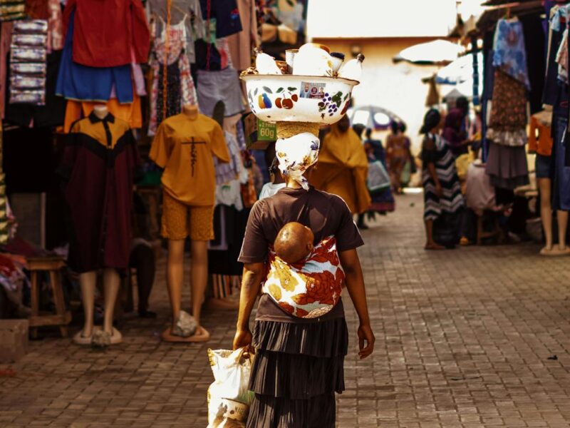 a woman walking down a street with a baby on her back