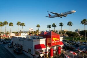 airplane flying over palm trees and store in california usa