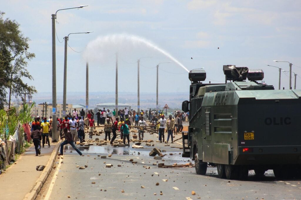 view of a police truck spraying water with water csanon on protesters on the street