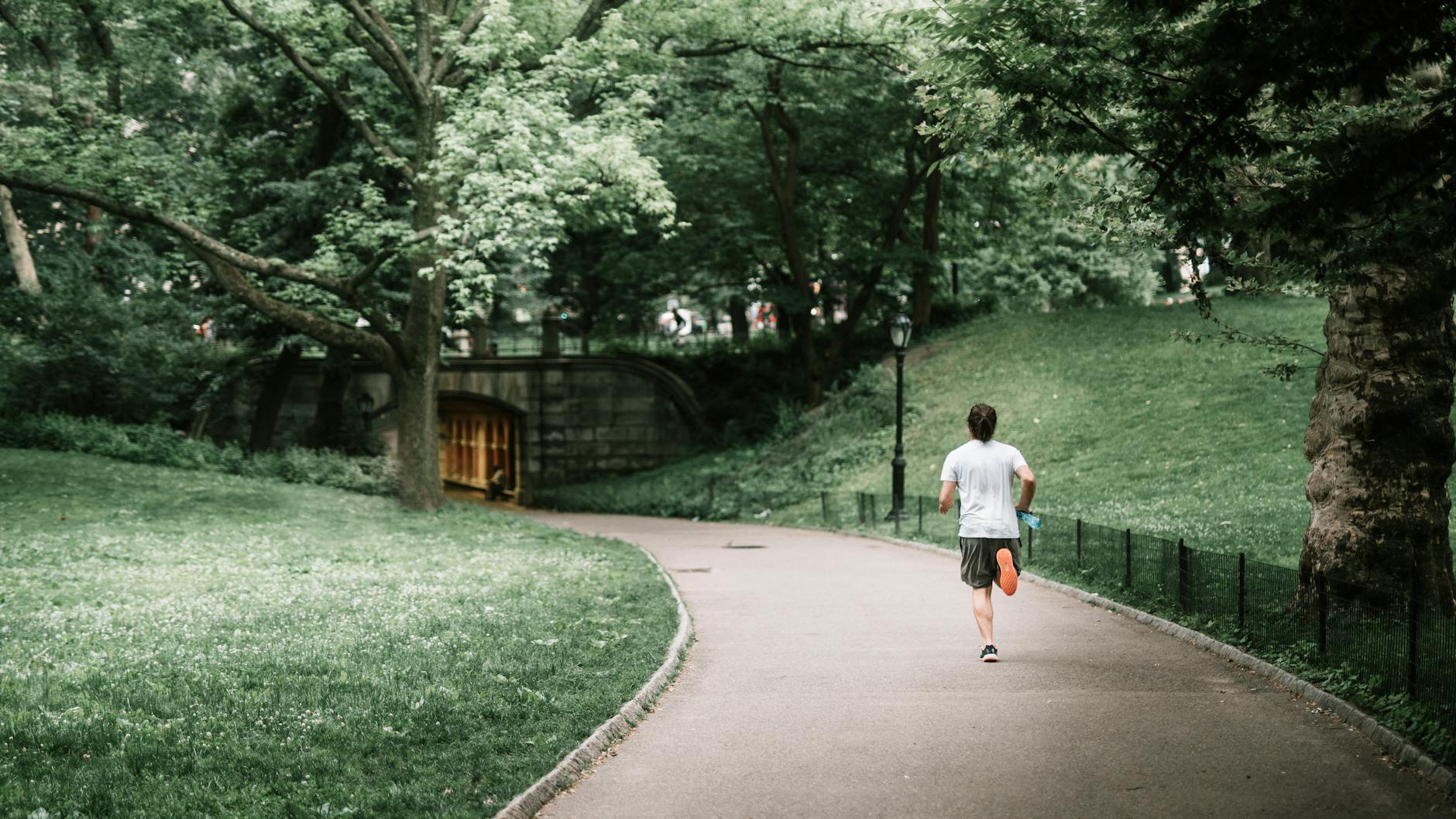 photo of man jogging on paved pathway