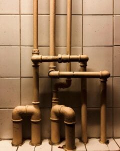 photograph of pipes near white tiles