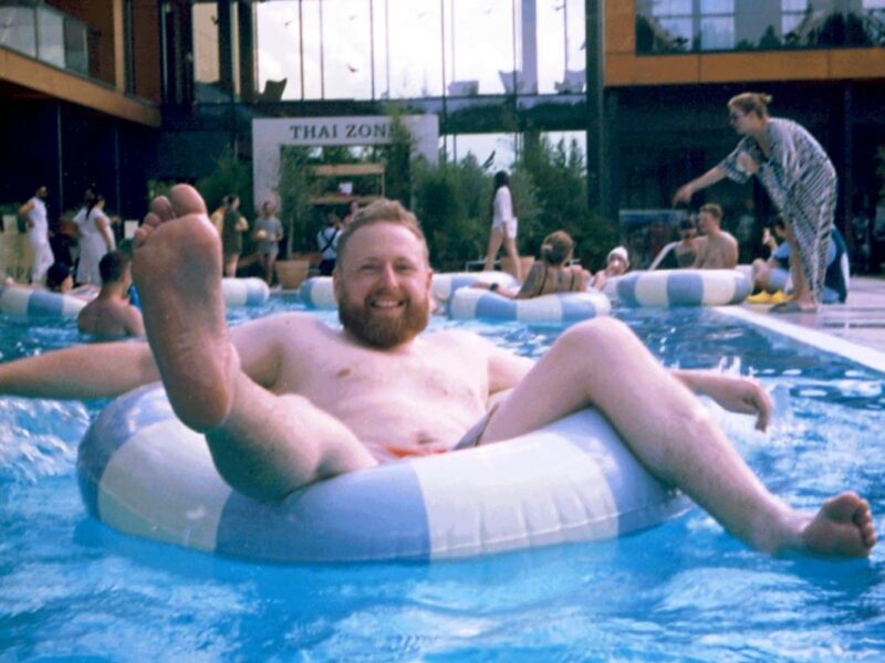 man relaxing on pool float in resort