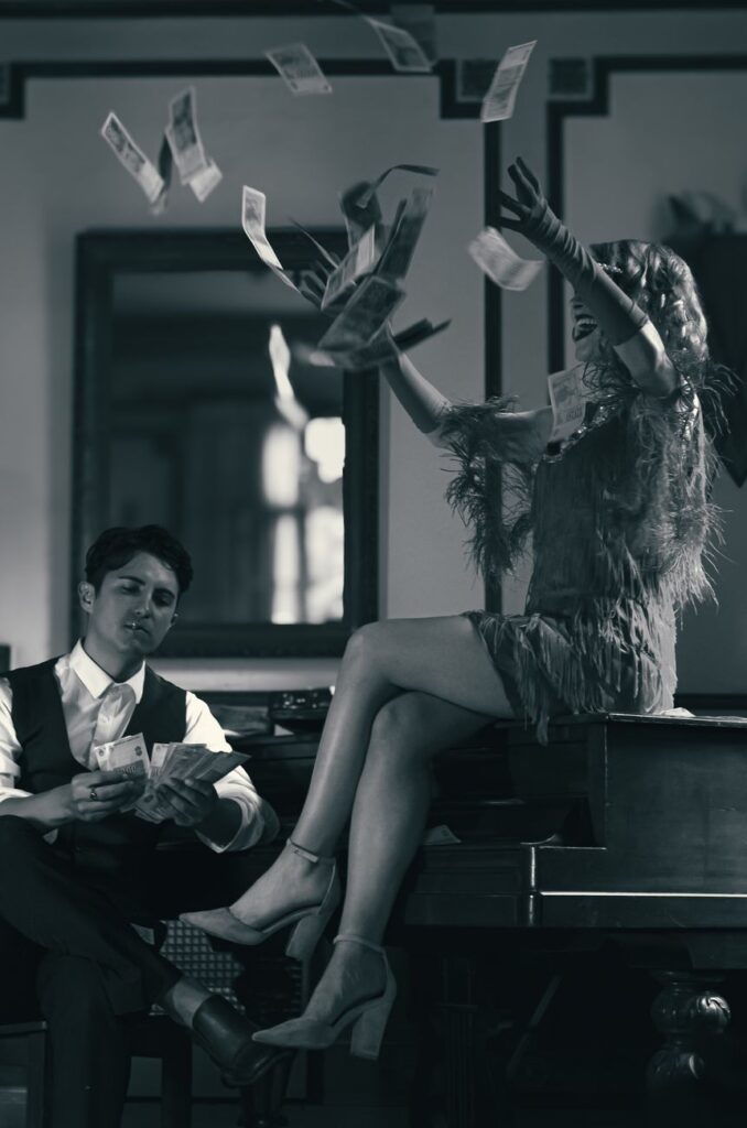 woman in dress throwing money in air next to man in vest and shirt