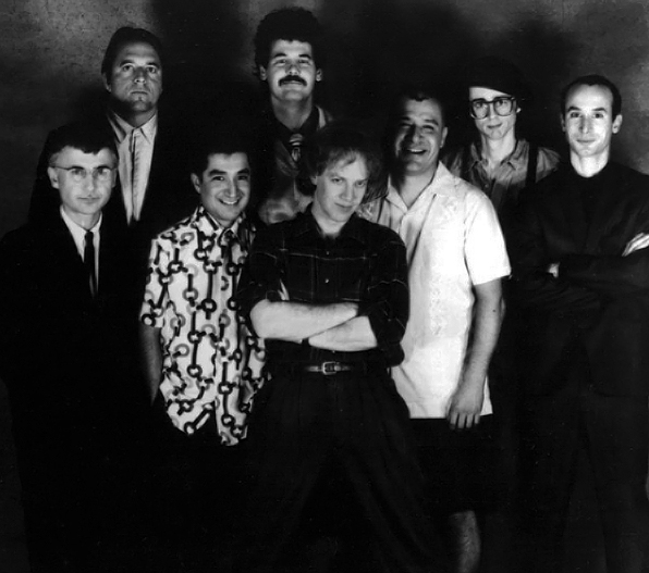 27 March 1987, OINGO BOINGO , (left to right) Dale Turner, Sam Phipps, John Avila, Steve Bartek, Danny Elfman, Johnny "Vatos" Hernandez, Mike Bacich, Leon Schneiderman , MCA Records, Public domain, via Wikimedia Commons