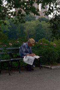 senior man reading newspaper in central park