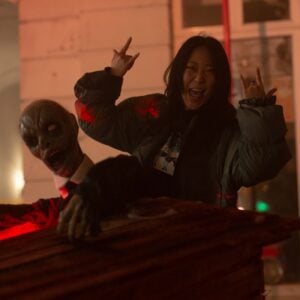 a woman in a jacket next to a zombie