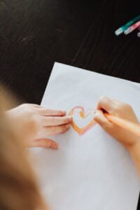 kid drawing a heart on paper